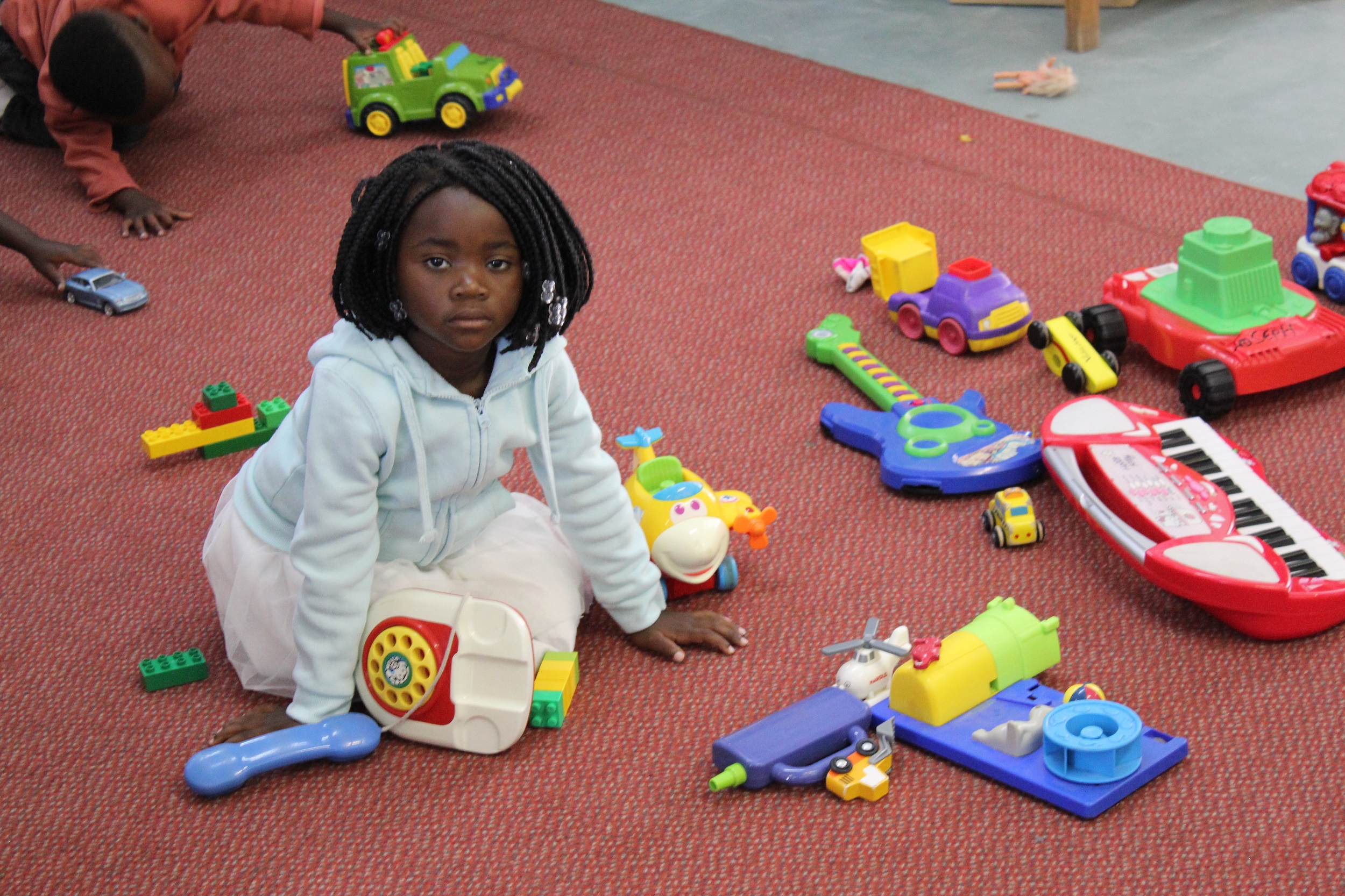 child sitting on play mat in preschool